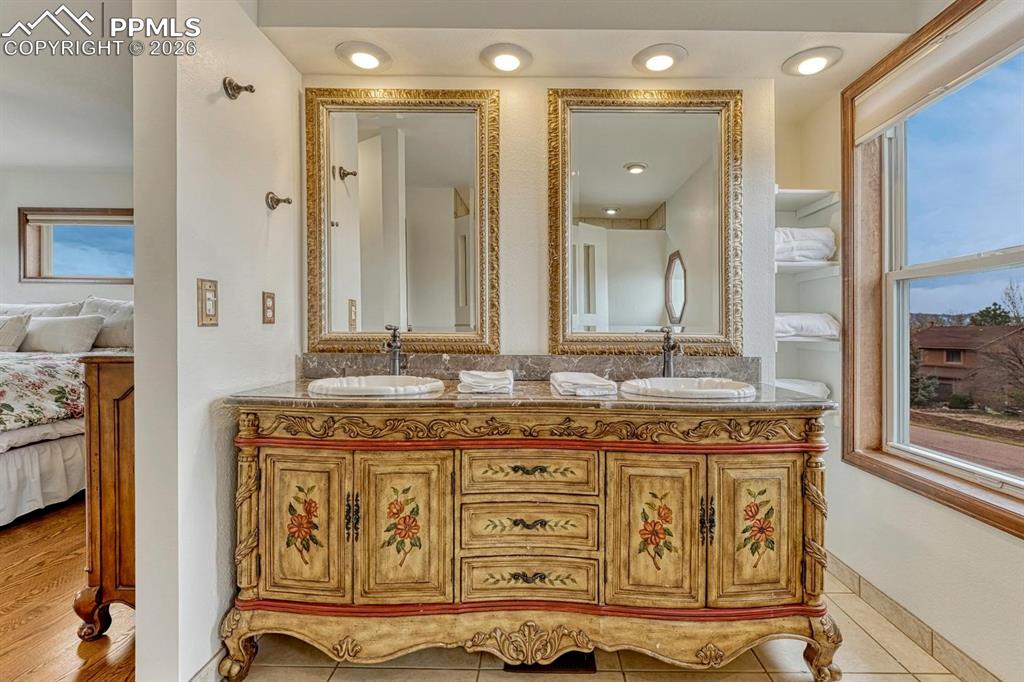 Image 31 of 44: Dual vanity featuring an ornate, hand-painted base with a stone countertop 