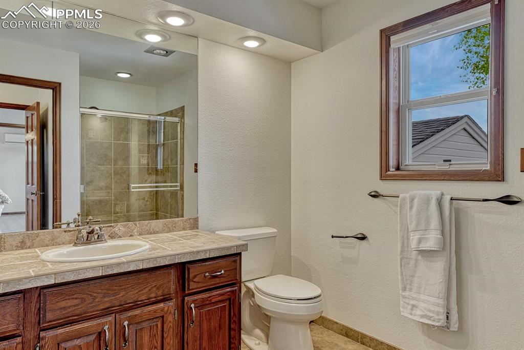 Image 32 of 44: Bathroom featuring a wood-finish vanity with tile countertop, undermount si