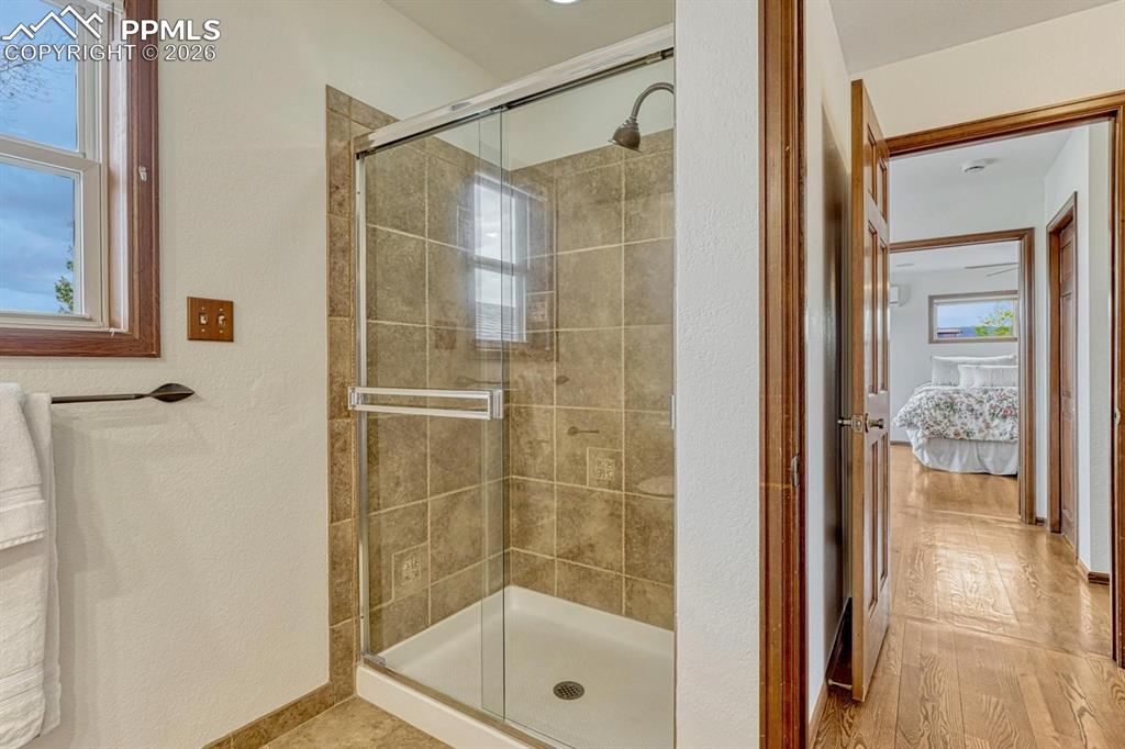 Image 33 of 44: Enclosed shower with glass sliding doors, neutral tile surround, and a corn