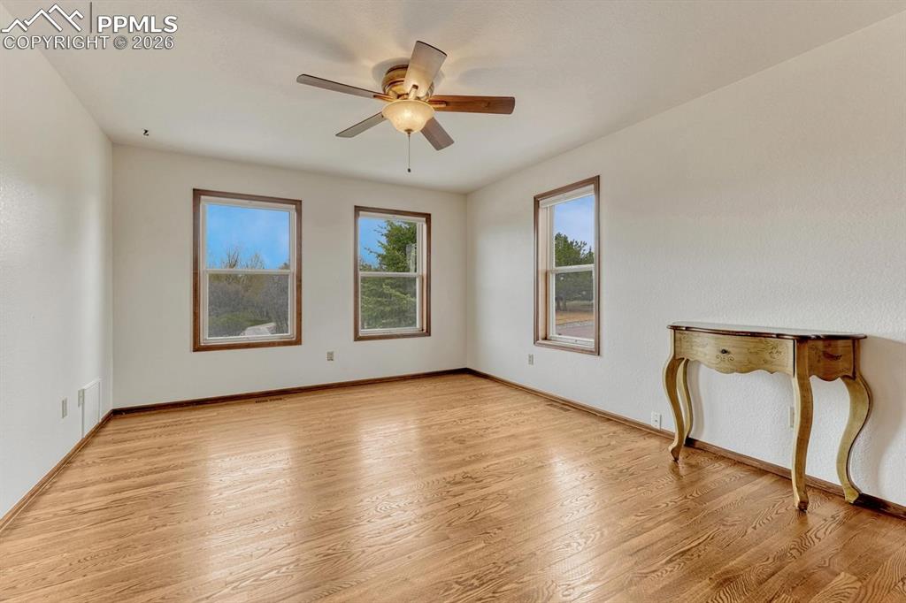 Image 34 of 44: Spacious room featuring wood-finish flooring and three large windows with w
