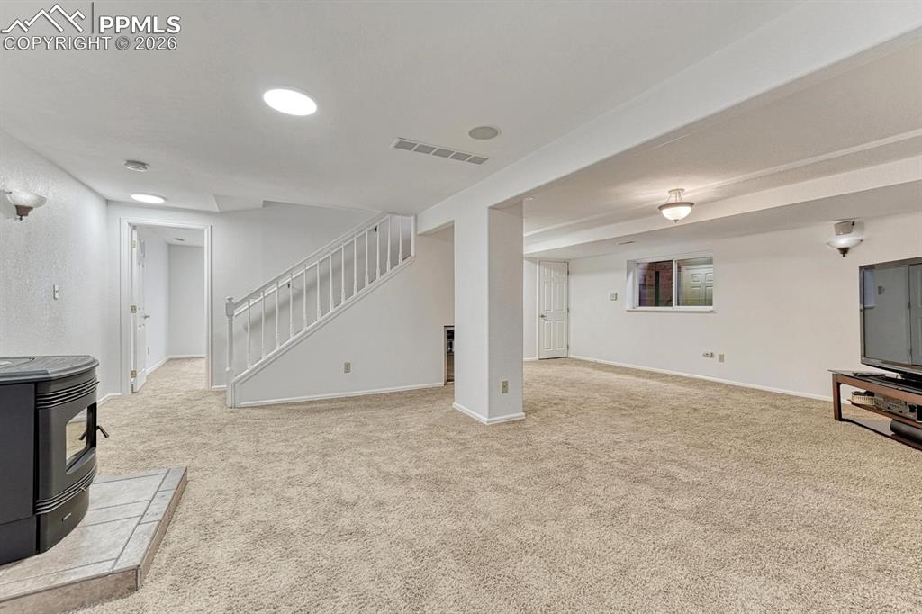 Image 36 of 44: Spacious lower-level living area with light beige carpeting and white paint