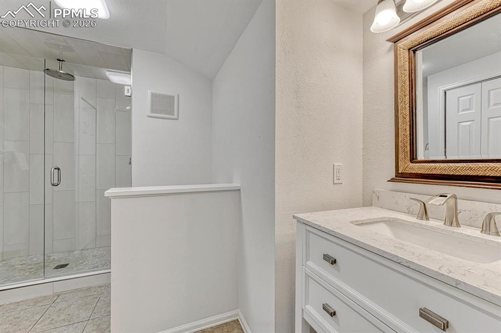 Image 40 of 44: Bathroom featuring a double vanity with stone countertop, dual undermount s