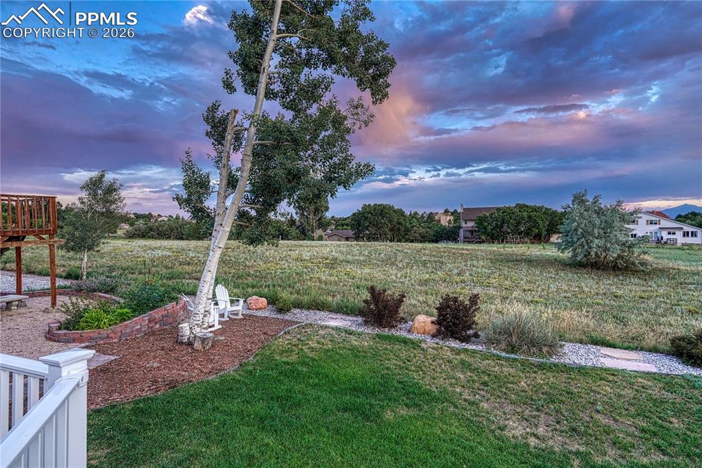 Image 43 of 44: Expansive backyard featuring a manicured lawn, established trees, and a tie