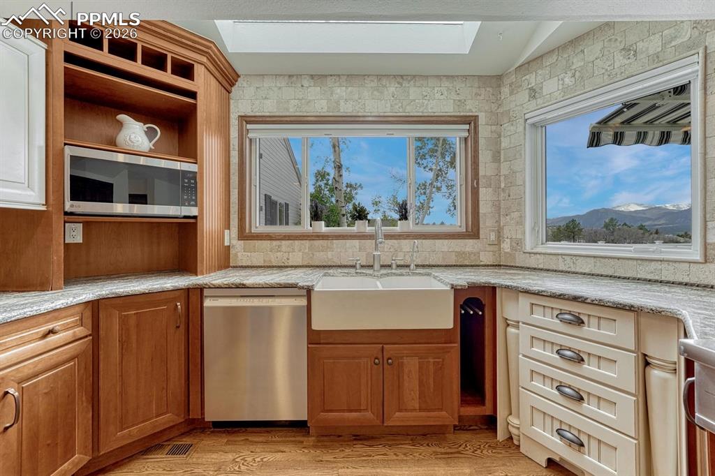 Image 5 of 44: Kitchen featuring a white farmhouse-style sink, granite countertops, and li