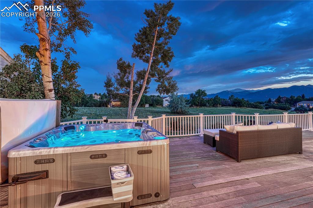 Image 8 of 44: Expansive outdoor deck featuring an illuminated hot tub and white railing o