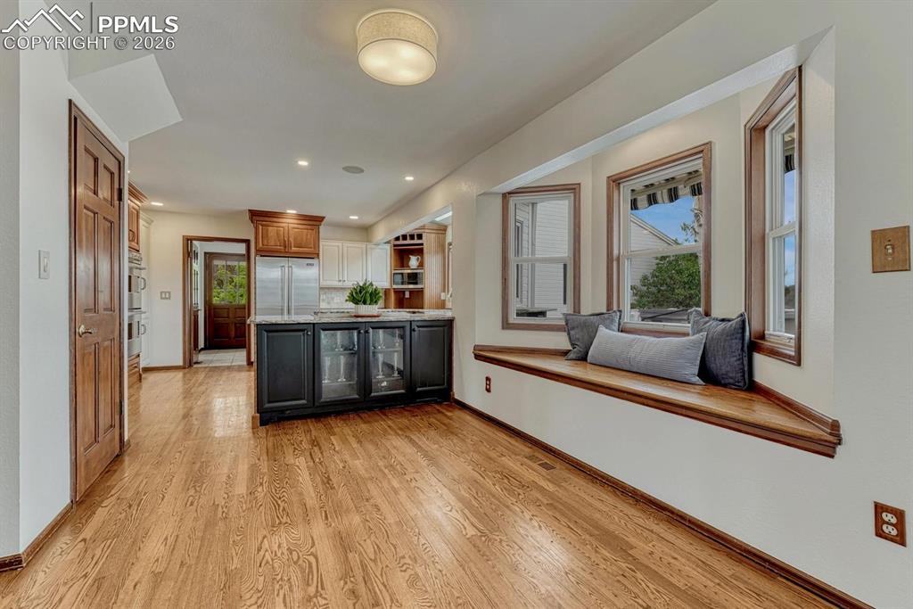 Image 9 of 44: Built-in window seat with wood trim, wood-finish flooring, kitchen island w