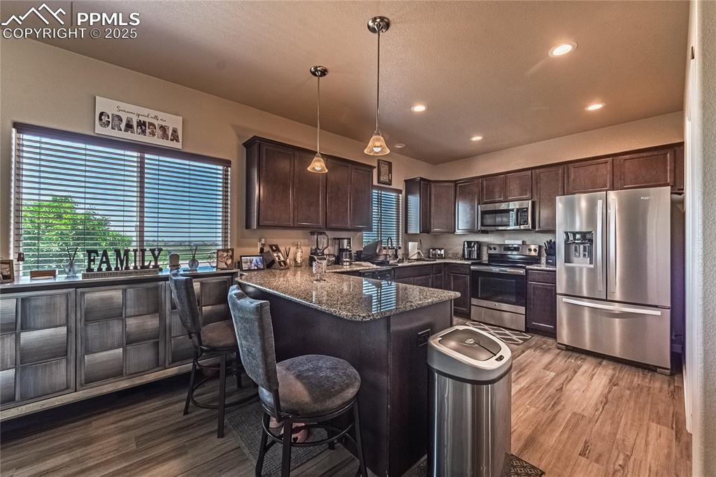 Image 10 of 33: Kitchen with appliances with stainless steel finishes, dark brown cabinetry