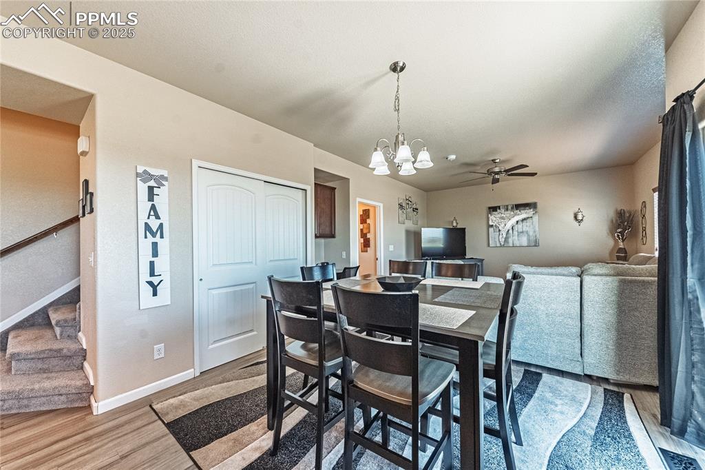Image 12 of 33: Dining space with wood finished floors, a chandelier, stairs, and ceiling f