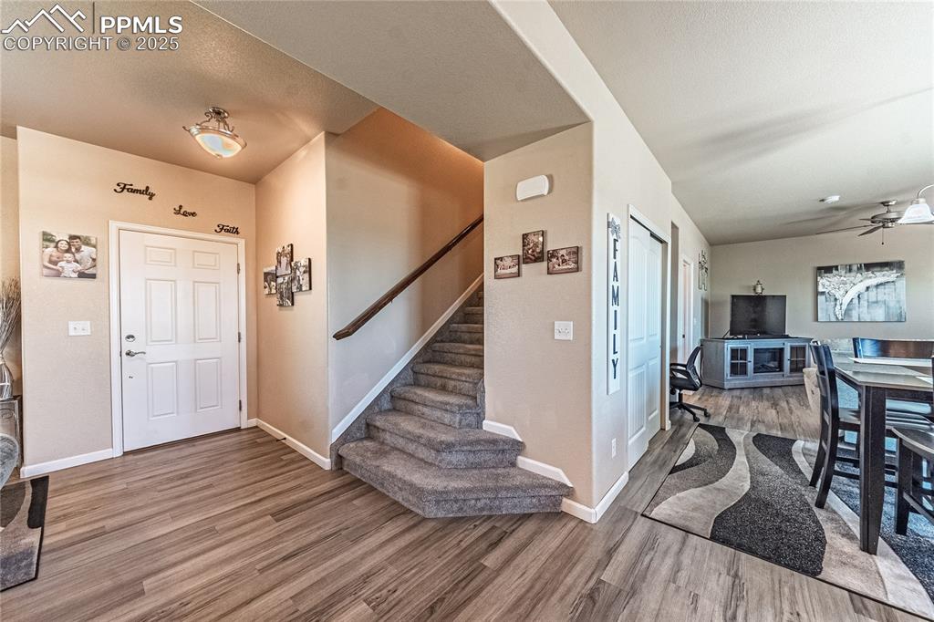 Image 16 of 33: Foyer entrance with wood finished floors, stairway, and a ceiling fan