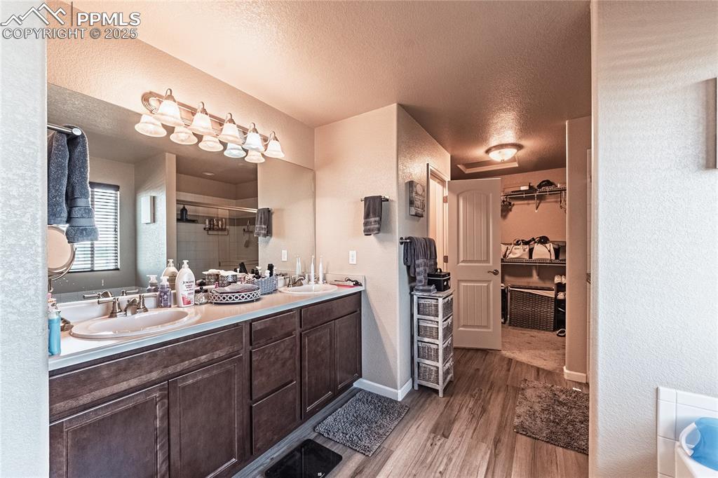 Image 30 of 33: Full bathroom with wood finished floors, a stall shower, double vanity, a t