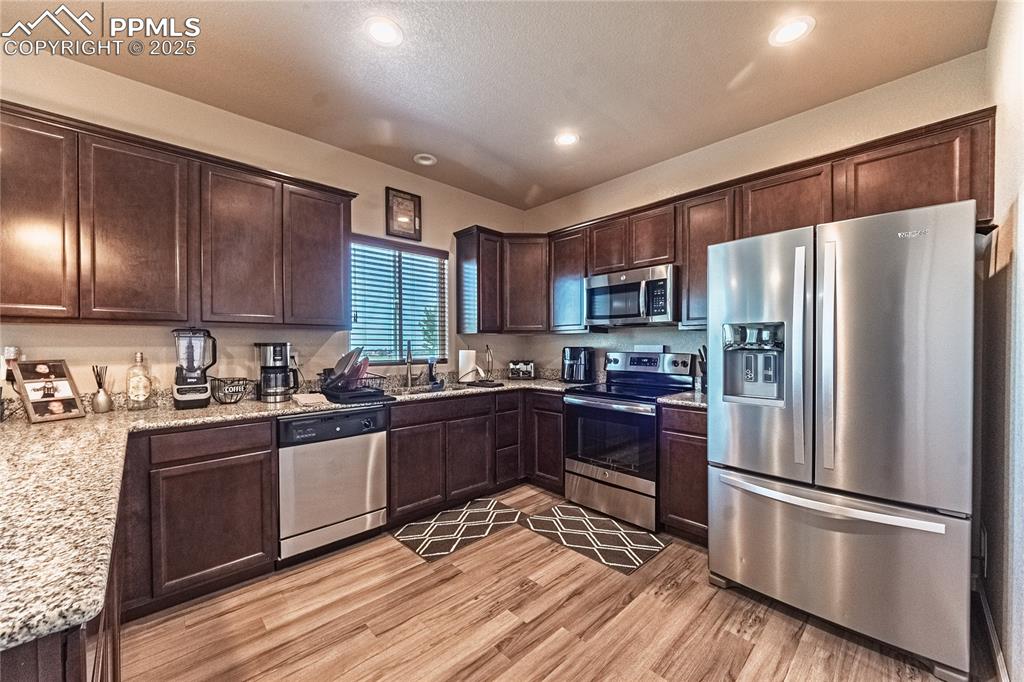 Image 8 of 33: Kitchen with appliances with stainless steel finishes, dark brown cabinets,