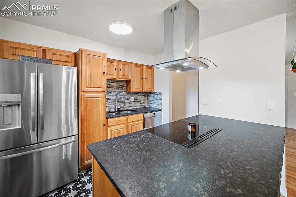 Image 12 of 49: kitchen with stone countertops, tile floors, and a tile backsplash