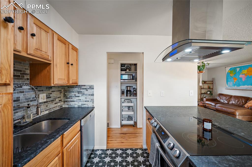 Image 13 of 49: kitchen with stone countertops, tile floors, and a tile backsplash