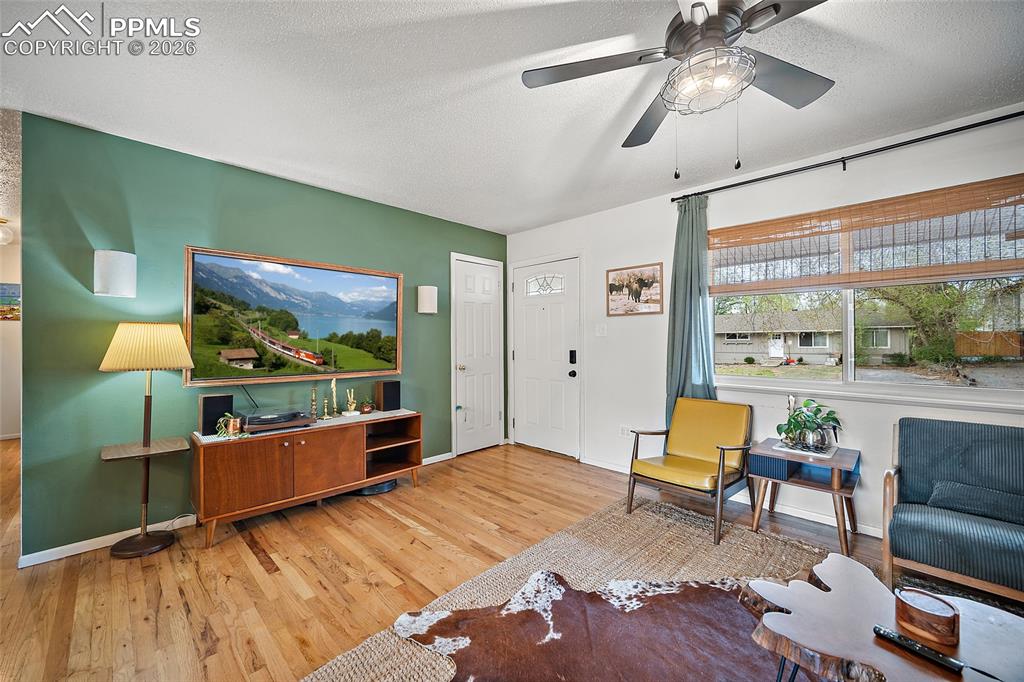Image 6 of 49: living room with real wood floors and a ceiling fan