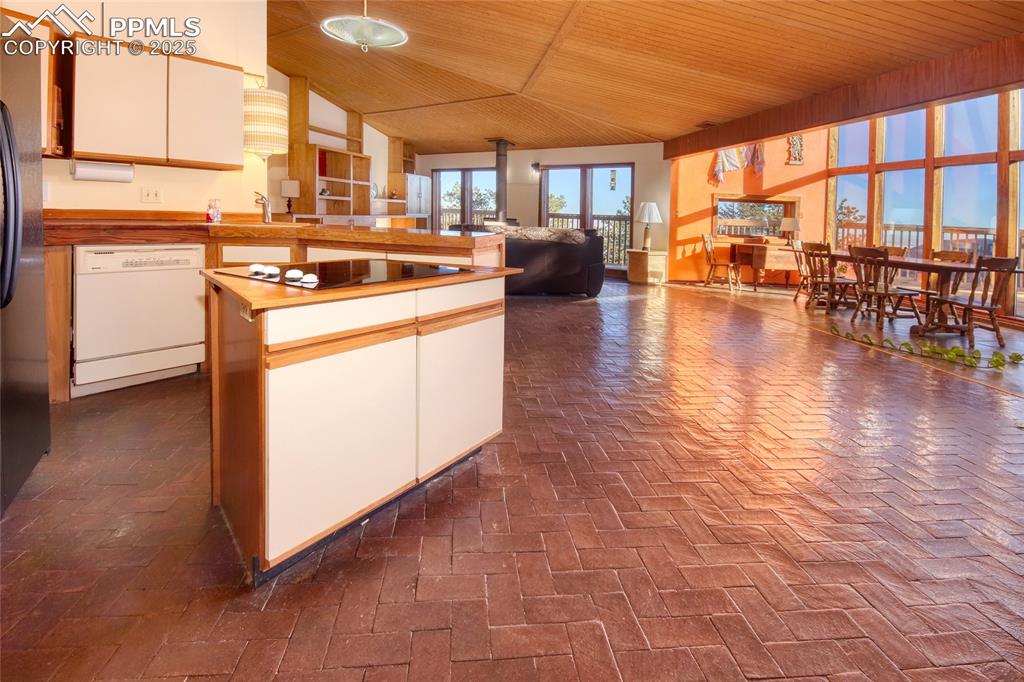 Image 10 of 33: Kitchen featuring white cabinets, wooden ceiling, open floor plan, black el