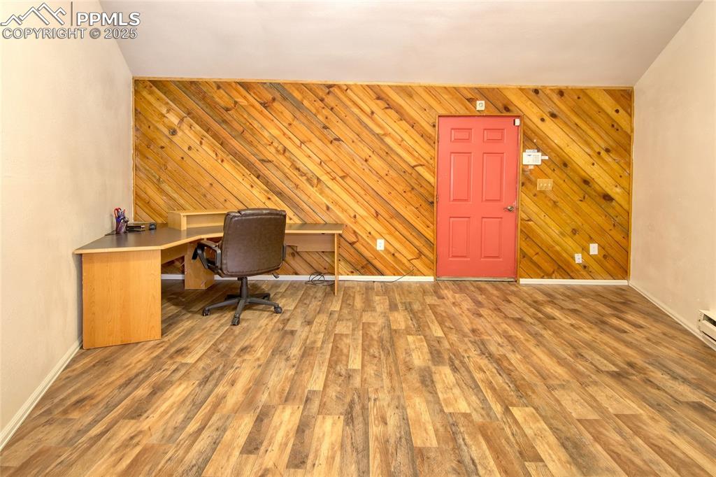 Image 17 of 33: Office area featuring wood walls, baseboards, and wood finished floors