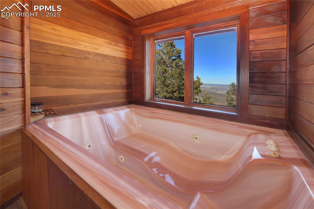 Image 20 of 33: Master Bathroom featuring vaulted ceiling, wood walls, and wooden ceiling. 