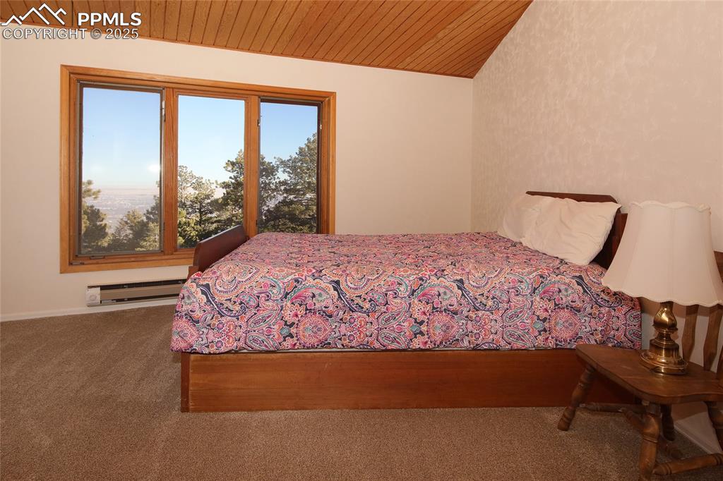 Image 21 of 33: Carpeted Master bedroom featuring baseboard heating, wooden ceiling, vaulte