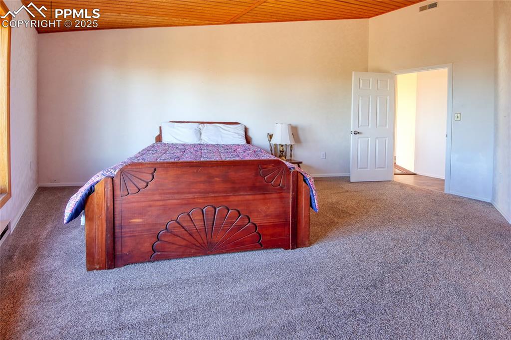Image 23 of 33: Bedroom featuring wooden ceiling, baseboards, carpet flooring, and visible 