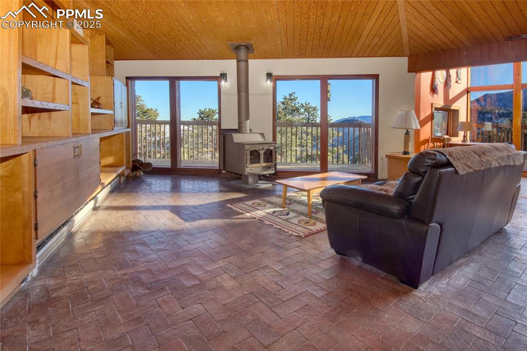 Image 6 of 33: Living room with wood ceiling and a wood stove