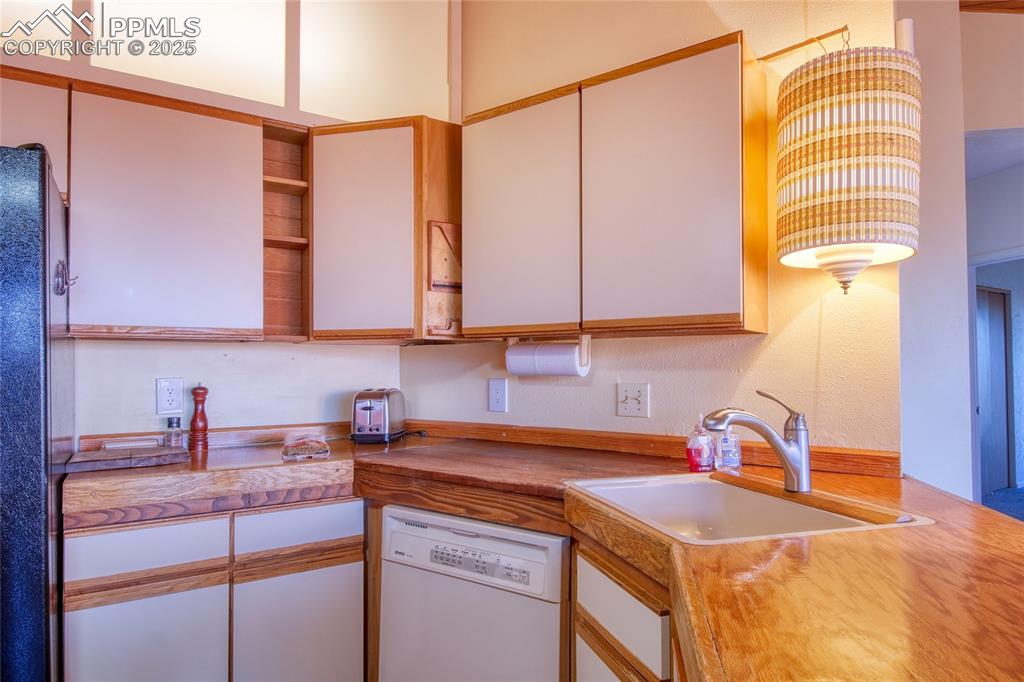 Image 9 of 33: Kitchen with dishwasher, white cabinets, a sink, and freestanding refrigera