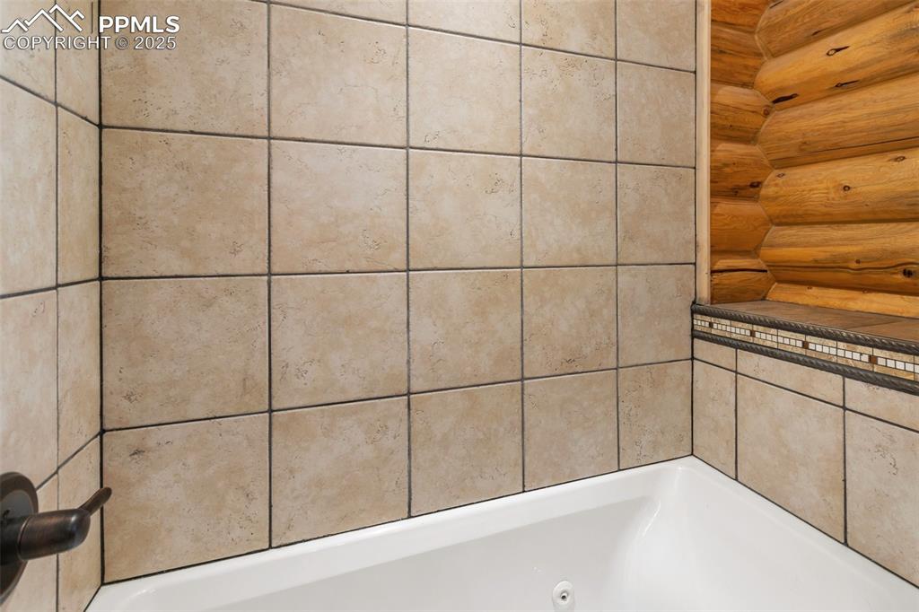 Image 29 of 46: Full bathroom featuring a jetted tub and rustic walls