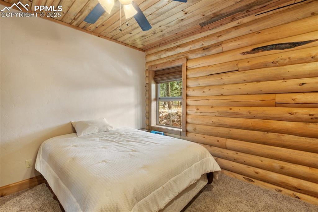 Image 31 of 46: Bedroom featuring wood ceiling, rustic walls, carpet floors, and a ceiling 