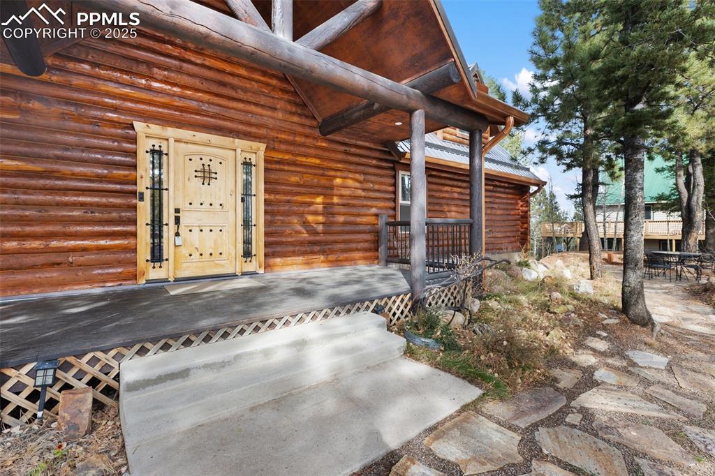 Image 6 of 46: Entrance to property with log siding, a deck, and a patio area