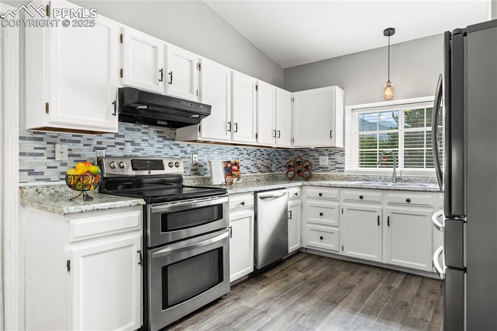 Image 4 of 21: Kitchen with appliances with stainless steel finishes, dark wood-type floor