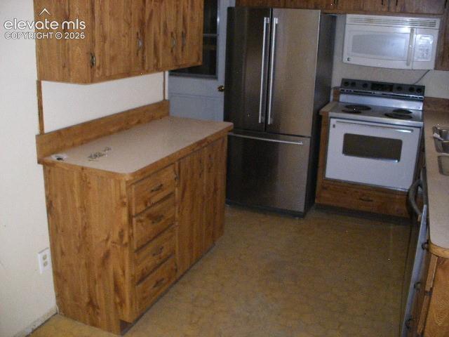 Image 13 of 35: Wood-finish cabinetry, light-toned countertops, stainless steel refrigerato