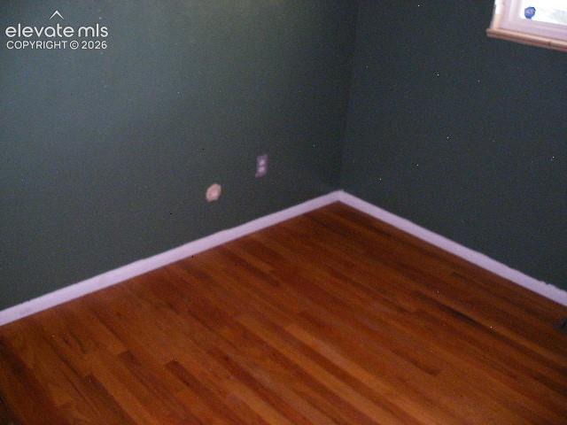 Image 23 of 35: Hardwood flooring with a natural finish, white trim, and a window with a li
