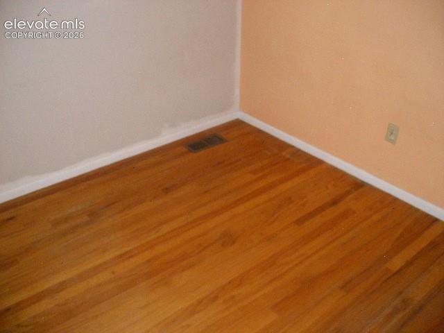 Image 25 of 35: Wood-finish flooring with white trim and a neutral wall color