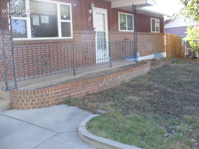 Image 5 of 35: Brick exterior with a covered porch, decorative metal railing, and a define