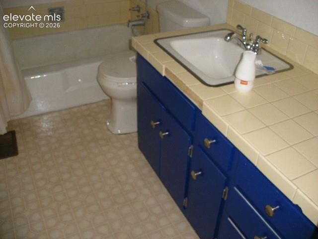 Image 9 of 35: Bathroom featuring a built-in vanity with blue cabinetry, a drop-in sink, a