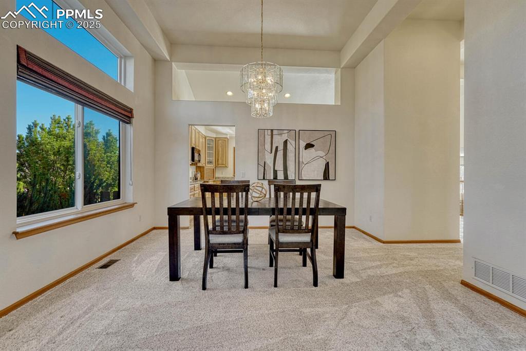 Image 10 of 50: Dining area featuring light colored carpet, a chandelier, and a high ceilin