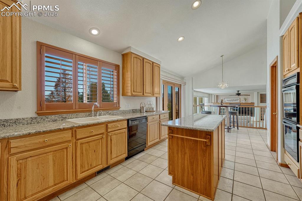 Image 15 of 50: Kitchen with light stone countertops, lofted ceiling, hanging light fixture