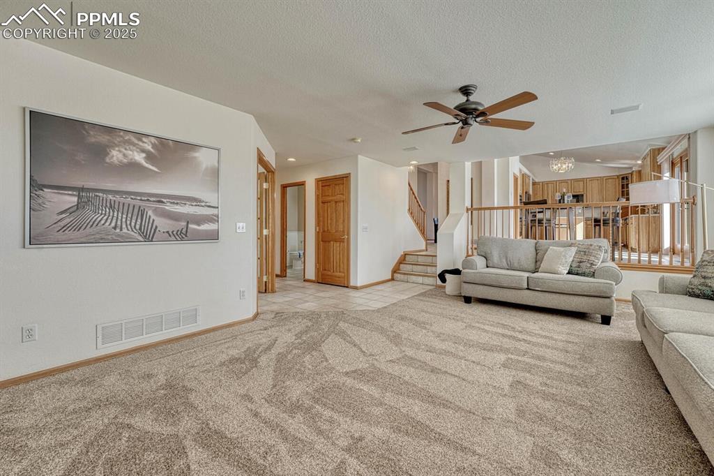Image 18 of 50: Living room featuring light carpet, a chandelier, stairway, a textured ceil