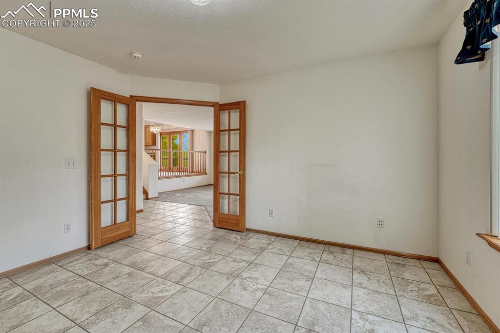 Image 22 of 50: Spare room with french doors, light tile patterned floors, and a textured c