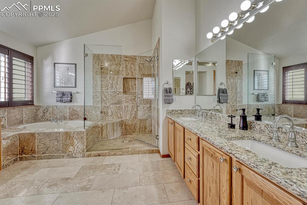 Image 27 of 50: Full bathroom with double vanity, lofted ceiling, a bath, and a shower stal