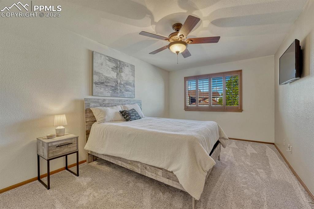 Image 33 of 50: Bedroom with a textured wall, carpet floors, and a ceiling fan