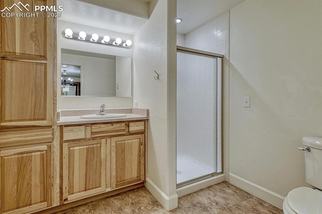 Image 39 of 50: Bathroom with a textured wall, a stall shower, vanity, and light tile patte