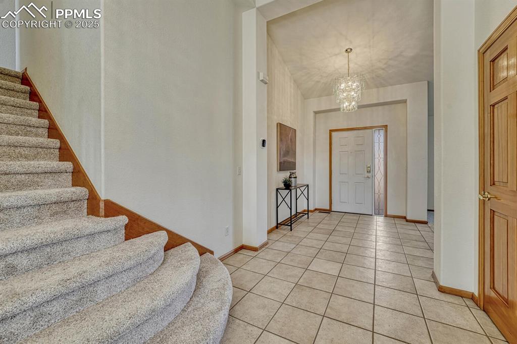 Image 4 of 50: Entrance foyer featuring light tile patterned flooring, a chandelier, and s