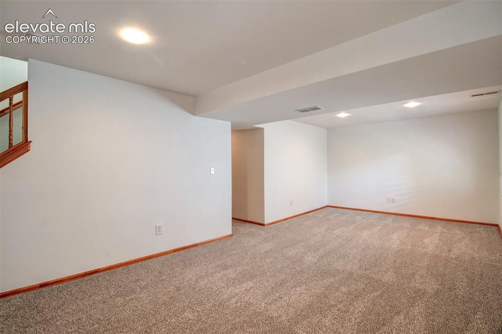 Image 26 of 37: Basement family room showing hallway access on the left that take you to tw