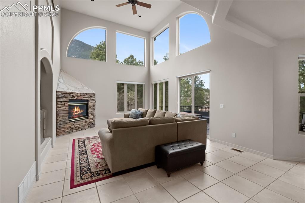 Image 15 of 40: Living room with vaulted ceilings, fireplace, mountain views, and mature tr