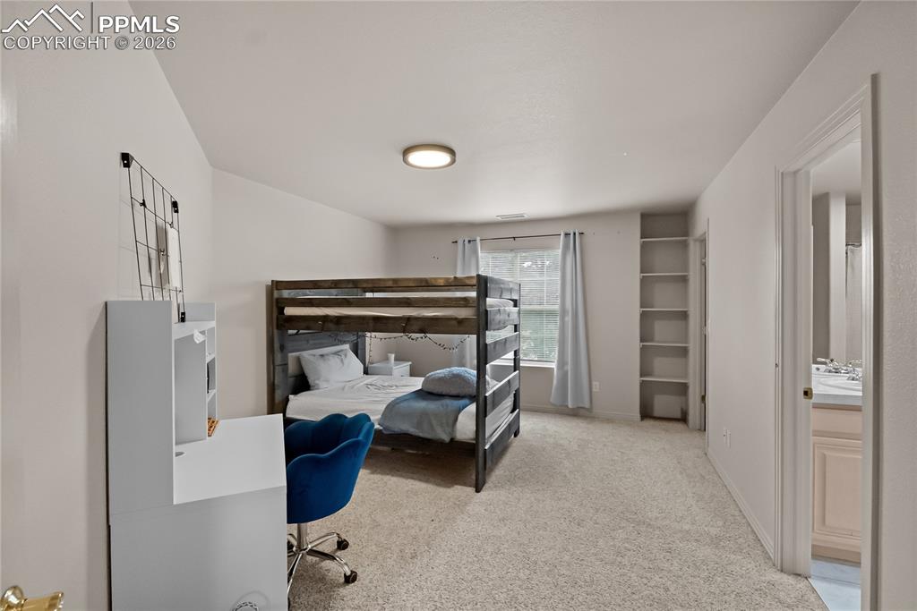 Image 24 of 40: Second bedroom with walk in closet, bookshelf and jack and Jill bathroom.