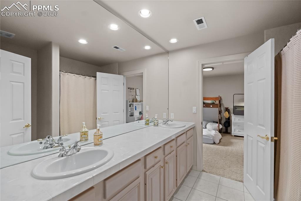 Image 25 of 40: Jack and Jill full bathroom with double vanity.