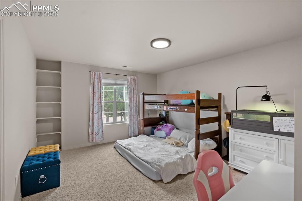 Image 26 of 40: Third bedroom with walk in closet, bookshelf and jack and Jill bathroom.