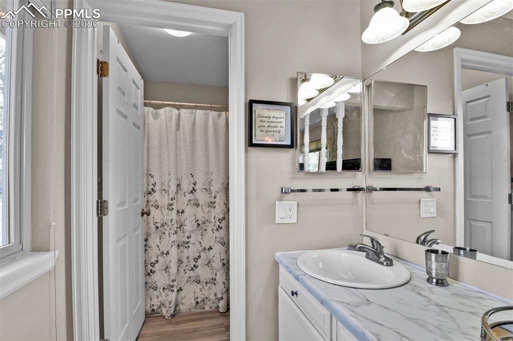 Image 32 of 41: Bathroom with double vanity, a shower with shower curtain, wood finished fl