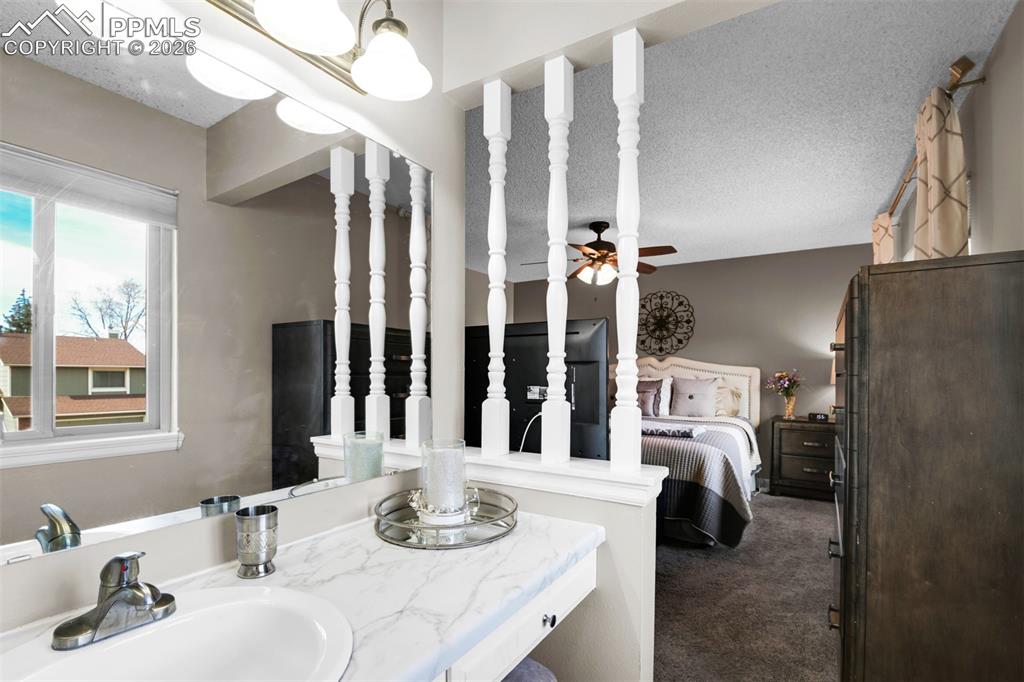 Image 33 of 41: Ensuite bathroom featuring vanity, dark carpet, ceiling fan, and a textured