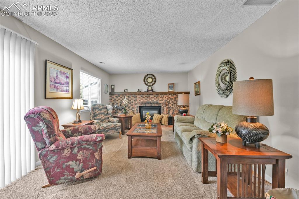 Image 35 of 41: Carpeted living room with a textured ceiling and a fireplace